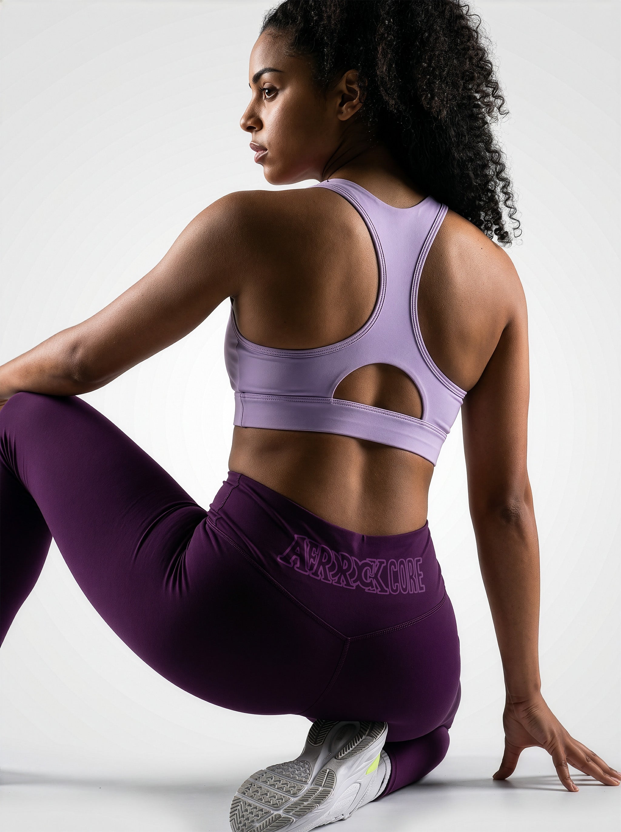 Back view of the AfroRock Core Purple yoga leggings and sports bra on model Kayla, showcasing the premium athletic fit and back branding details.⁠ 