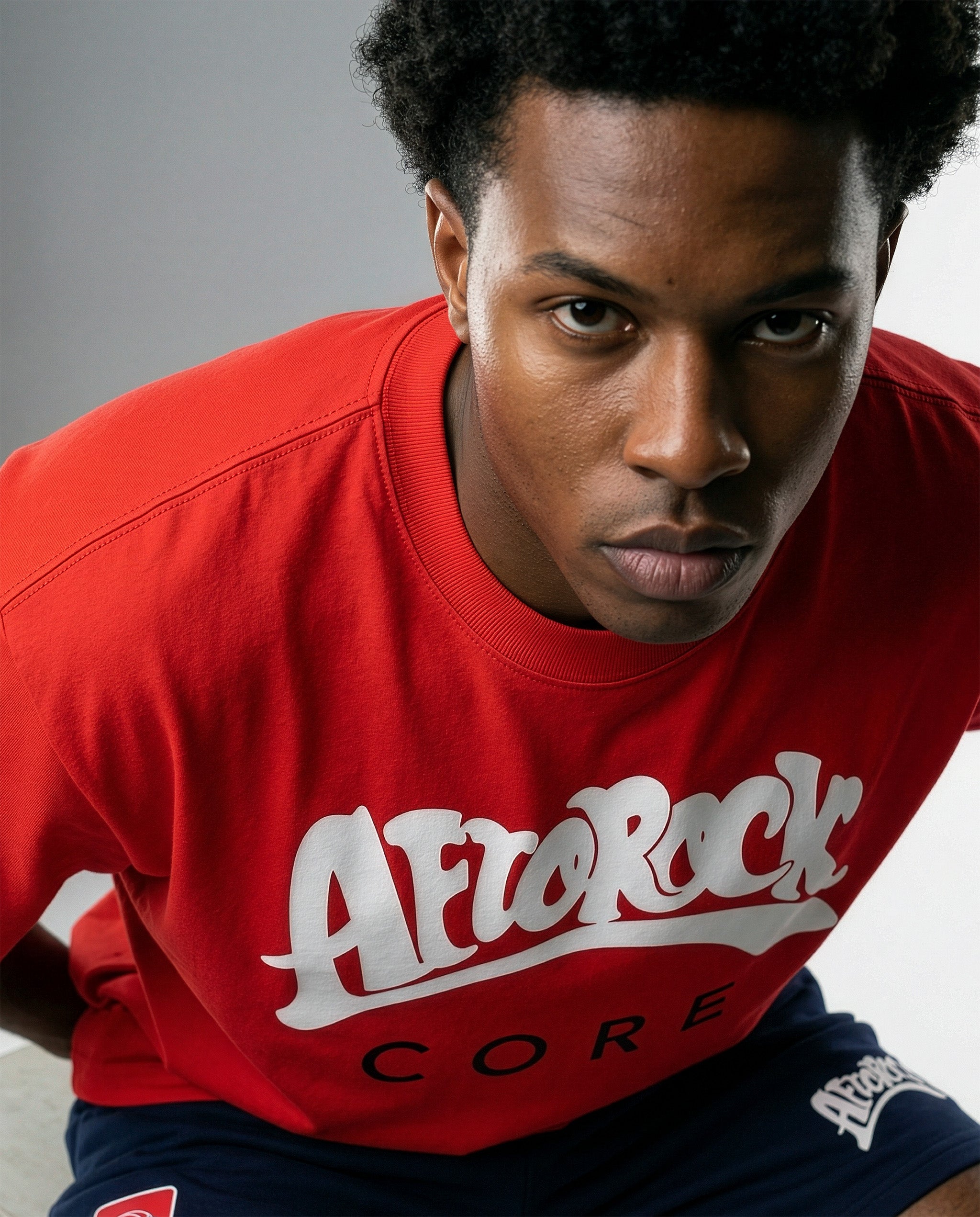Model Terrell in the AfroRock Core Sorona Quick-Dry Cooling T-Shirt in Crimson Red. Sustainable midweight streetwear graphic tee featuring advanced plant-based eco-fiber technology and bold chest branding by AfroRock.