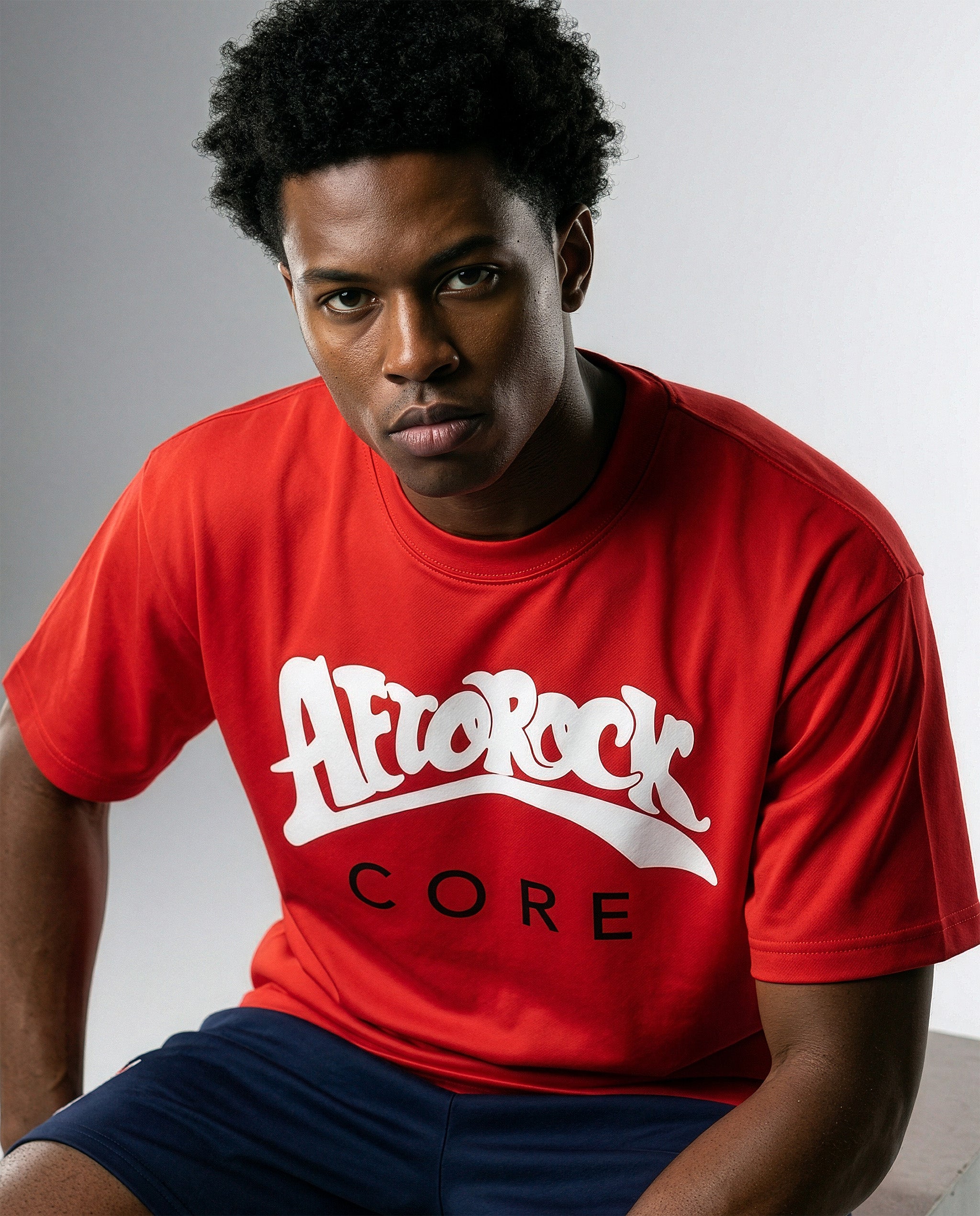Model Terrell in the AfroRock Core Sorona Quick-Dry Cooling T-Shirt in Crimson Red. Sustainable midweight streetwear graphic tee featuring advanced plant-based eco-fiber technology and bold chest branding by AfroRock.