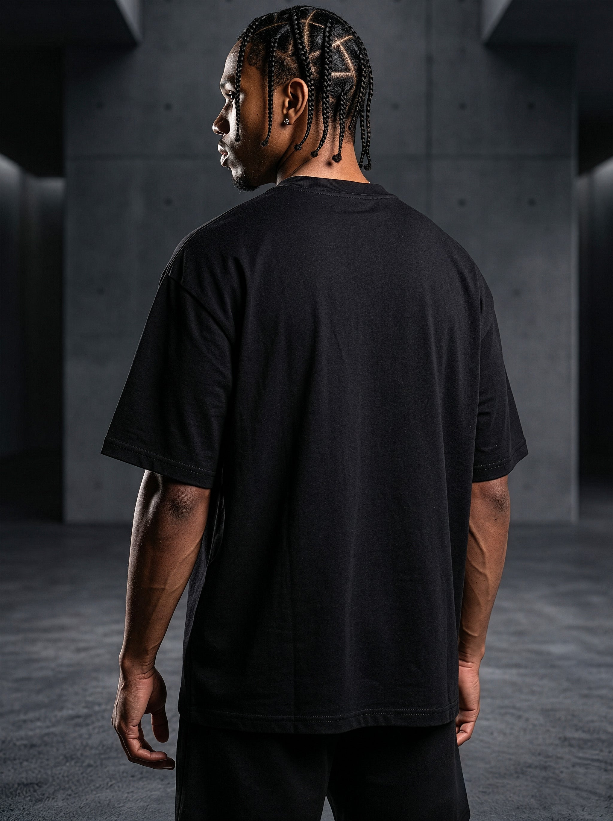 Rear View Studio product photography of model Jason in the AfroRock Core streetwear collection. He wears the AfroRock Basketball Vintage Graphic Tee in Pitch Black, an oversized 260gsm cotton shirt with an expansive front graphic of a basketball and hoop, a vintage weather-crackle print finish, and an athletic team badge. Industrial studio lighting highlights a premium sport-heritage lifestyle aesthetic.