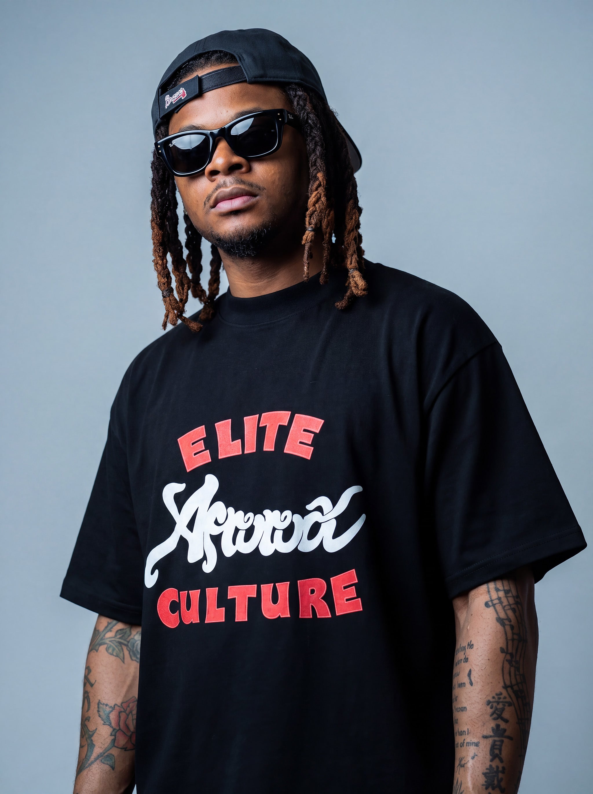 Brand founder Kal Afrorock modeling the Elite AfroRock Culture Oversized Boxy T-Shirt in Pitch Black. Heavyweight 300gsm seamless cotton streetwear tee featuring custom hand-drawn graphics and an intentional drop-shoulder silhouette.