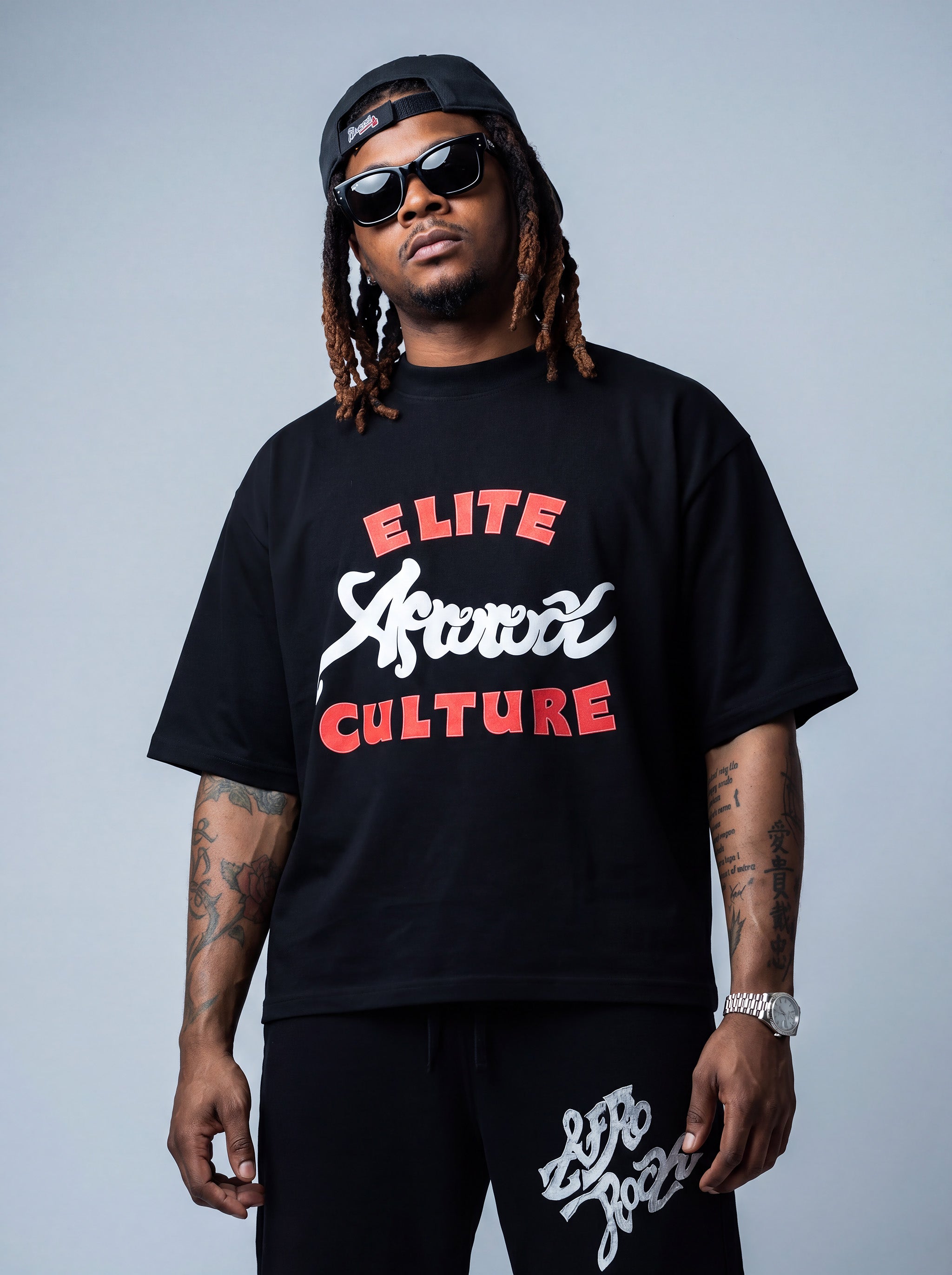 Brand founder Kal Afrorock modeling the Elite AfroRock Culture Oversized Boxy T-Shirt in Pitch Black. Heavyweight 300gsm seamless cotton streetwear tee featuring custom hand-drawn graphics and an intentional drop-shoulder silhouette.