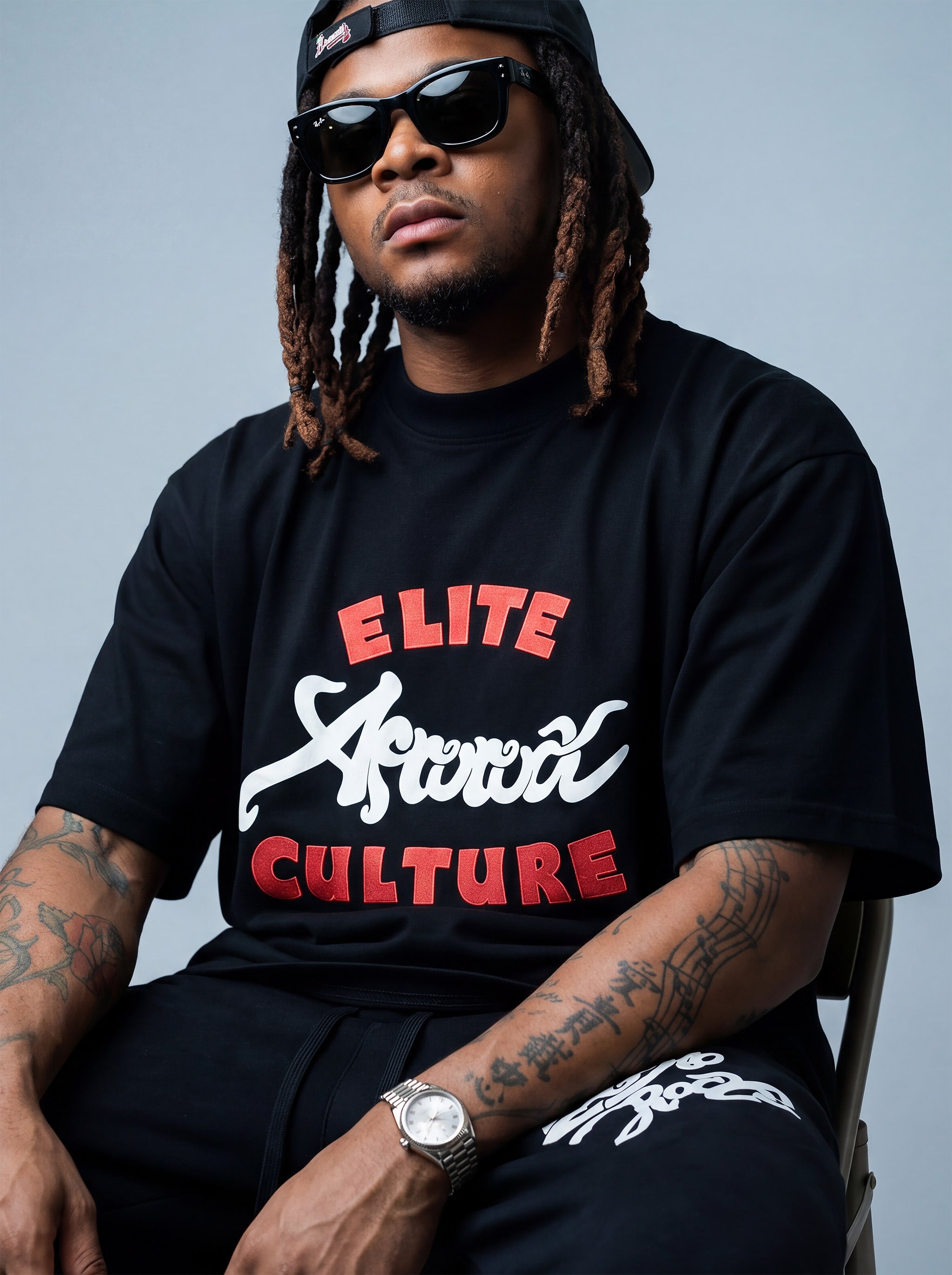 Brand founder Kal Afrorock modeling the Elite AfroRock Culture Oversized Boxy T-Shirt in Pitch Black. Heavyweight 300gsm seamless cotton streetwear tee featuring custom hand-drawn graphics and an intentional drop-shoulder silhouette.