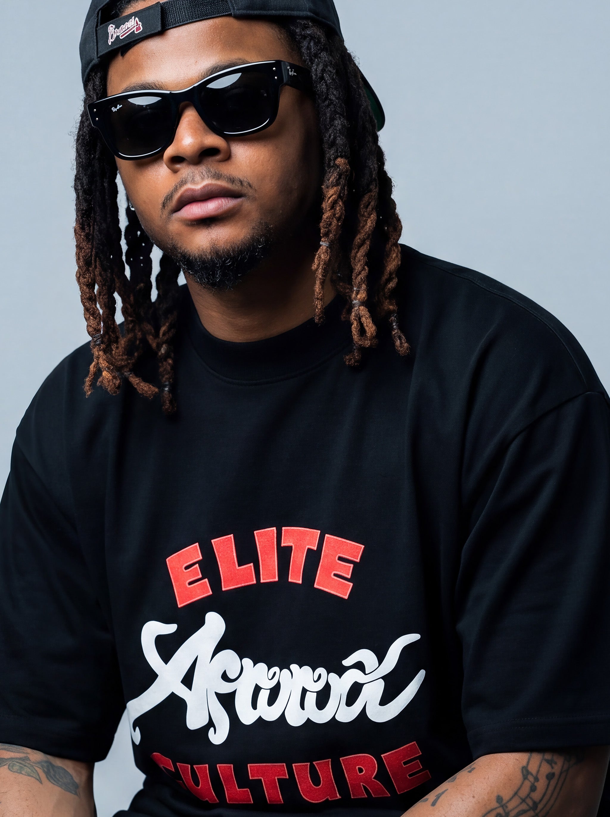 Brand founder Kal Afrorock modeling the Elite AfroRock Culture Oversized Boxy T-Shirt in Pitch Black. Heavyweight 300gsm seamless cotton streetwear tee featuring custom hand-drawn graphics and an intentional drop-shoulder silhouette.