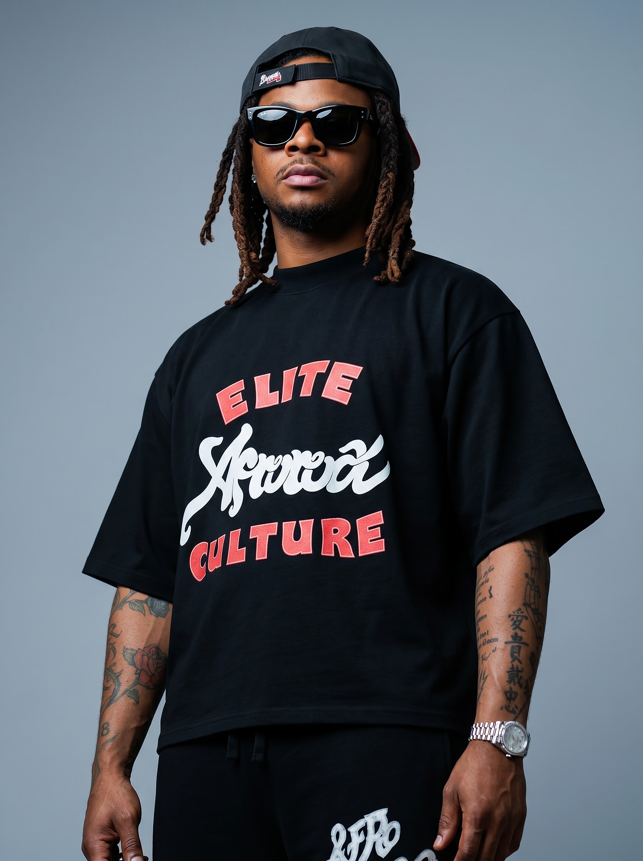 Brand founder Kal Afrorock modeling the Elite AfroRock Culture Oversized Boxy T-Shirt in Pitch Black. Heavyweight 300gsm seamless cotton streetwear tee featuring custom hand-drawn graphics and an intentional drop-shoulder silhouette.