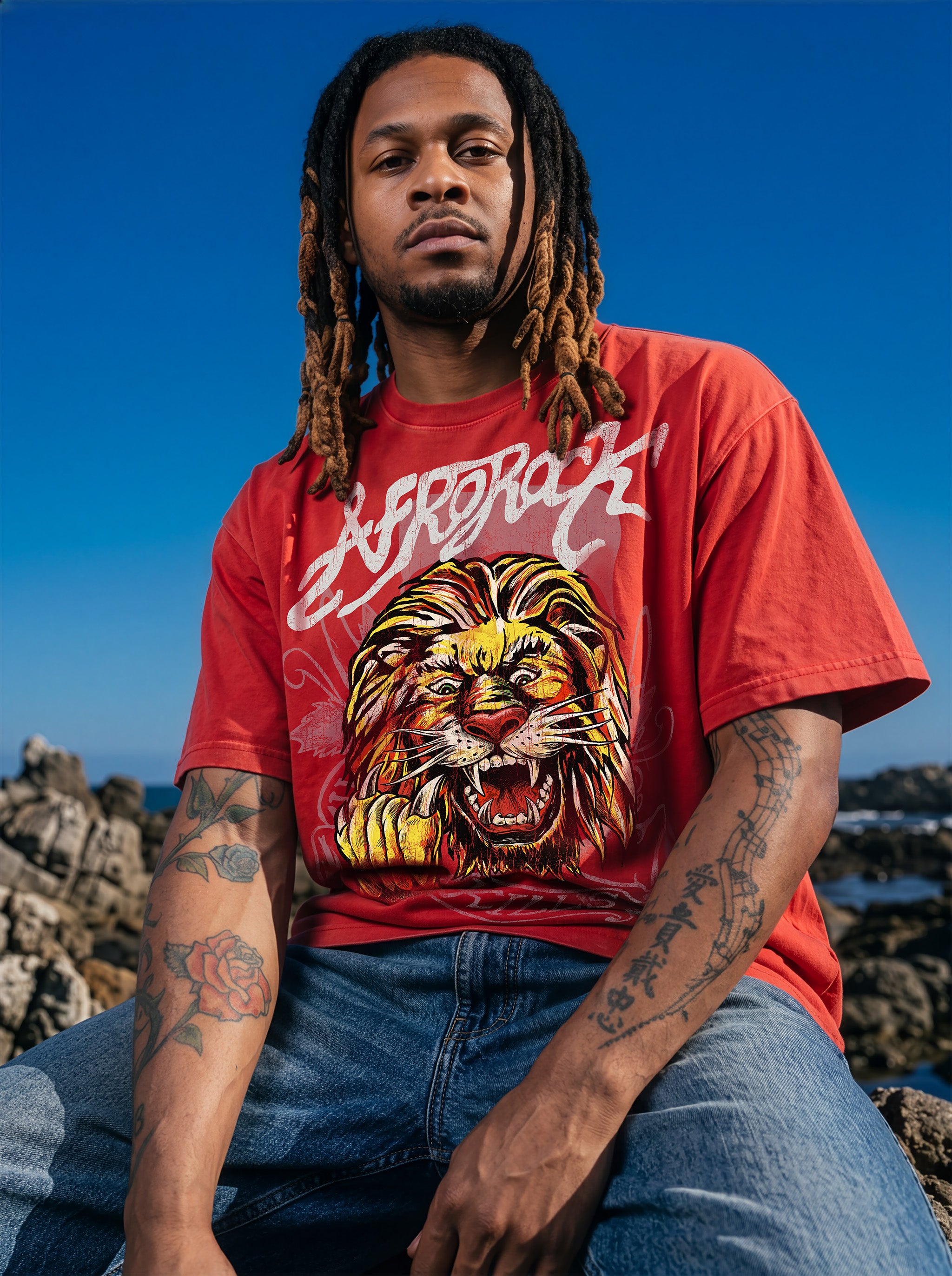Brand founder Kal Afrorock modeling the AfroRock Ishiagu Vintage Mineral Wash Boxy Tee in Fade Crimson. Premium 360gsm heavyweight cotton streetwear t-shirt featuring a custom hand-drawn West African Ishiagu Lion graphic.