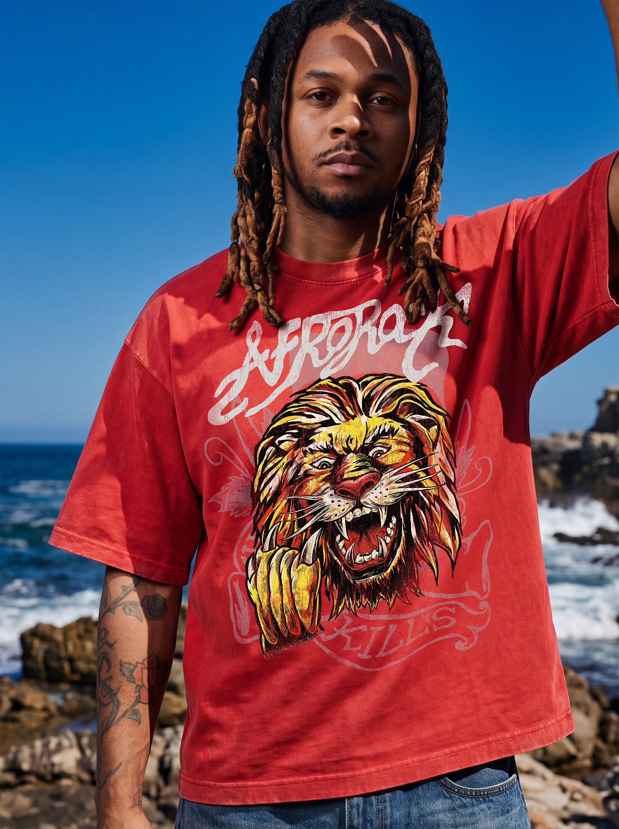 Brand founder Kal Afrorock modeling the AfroRock Ishiagu Vintage Mineral Wash Boxy Tee in Fade Crimson. Premium 360gsm heavyweight cotton streetwear t-shirt featuring a custom hand-drawn West African Ishiagu Lion graphic.
