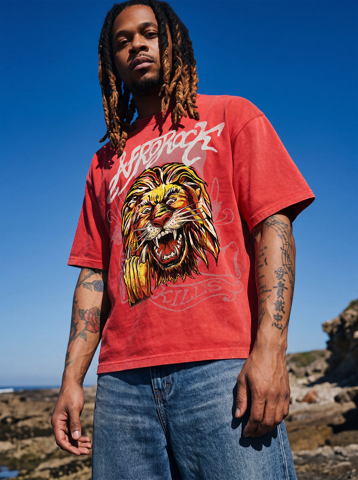 Brand founder Kal Afrorock modeling the AfroRock Ishiagu Vintage Mineral Wash Boxy Tee in Fade Crimson. Premium 360gsm heavyweight cotton streetwear t-shirt featuring a custom hand-drawn West African Ishiagu Lion graphic.